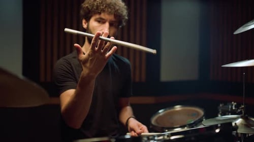 Musician Twirling Drumstick in Studio, Rock Drummer Sitting in Concert Hall