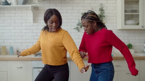 Young Women Dancing Together in Bright Kitchen
