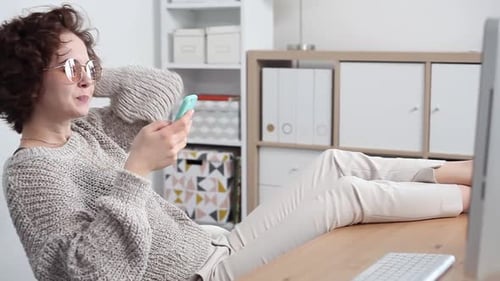 Woman Browsing Mobile Phone with Feet on Desk