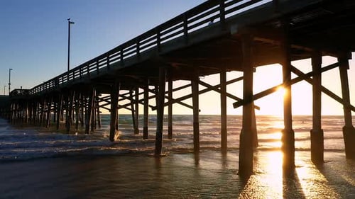 View of the pier at Newport Beach as sun shines from behind