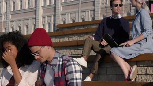 Multiethnic Students Sitting Outside the University Talking, Using Phone, Laptop