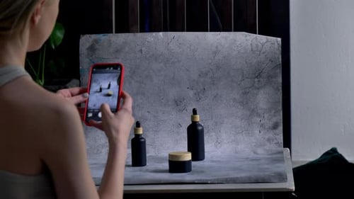 Stylist Photographing Black Cosmetic Products with Mobile Phone