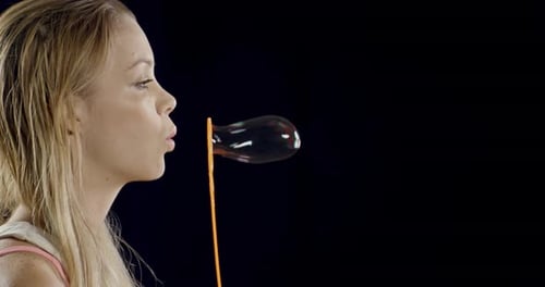 Woman Blowing Bubbles on Black Background