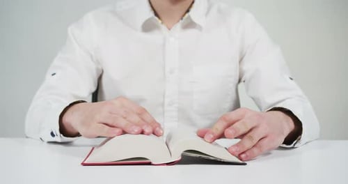 Person liest ein Buch auf dem Schreibtisch