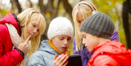 Children Gather Around Tablet in Autumn Woods