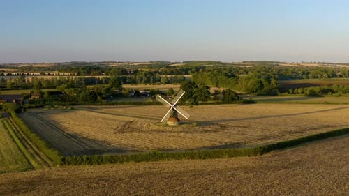 Picturesque Windmill Amidst Golden Fields in Rural Setting
