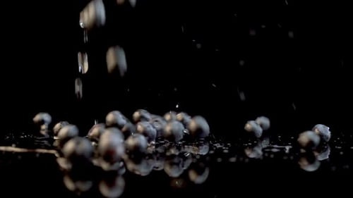 Blueberries Dropping with Water against Black Background