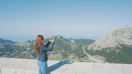 Attractive Girl Photographs a Beautiful Mountain View on a Cell Phone