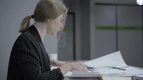 Side View of Busy Young Woman Analyzing Diagrams in Office
