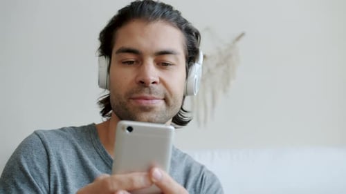 Young Man Listening to Music on Phone Indoors