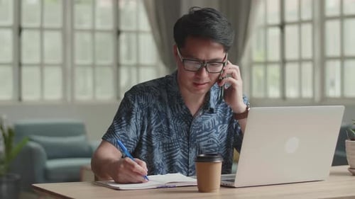 Young Adult Working from Home with Laptop and Phone