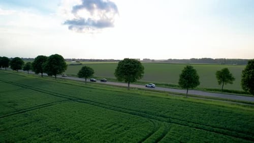 Side view of cars driving on scenic rural road. Transport drone shot.