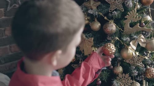 Child Decorating Christmas Tree with Golden Baubles