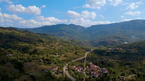 Steep green mountains, deep forest and mountain road, beautiful valley and village houses
