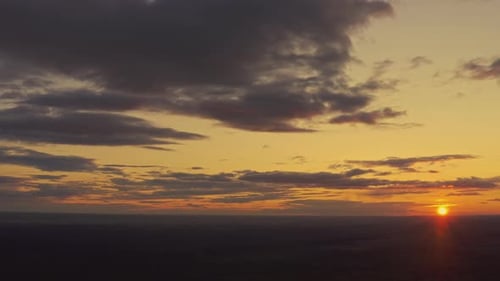 Luftaufnahme des Sonnenunterganghimmels über der grünen Waldlandschaft am sonnigen Abend
