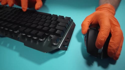 Person in Orange Gloves Works with Keyboard and Mouse