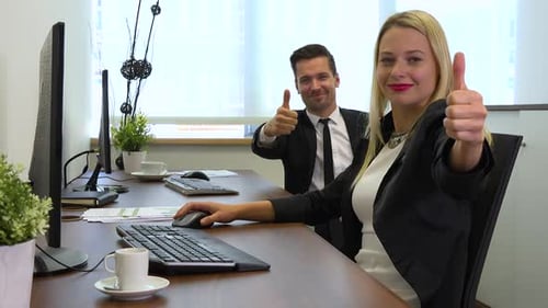 Two Office Workers, Man and Woman, Work on Computers and Show Thumbs up To the Camera