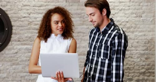 Colleagues Discussing Data on Laptop in Modern Office