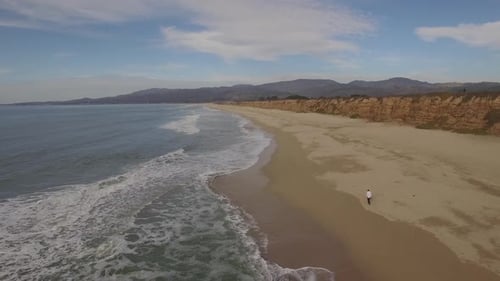 Scenic Aerial View of Man Walking on Beach
