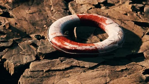 Distressed Lifebuoy Resting on Rugged Rocks with Panning Camera Movement
