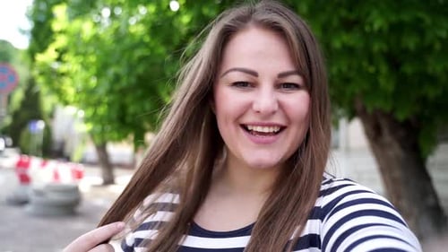 Smiling Woman Waving and Talking Outdoors