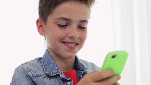 Boy Smiles While Using a Smartphone