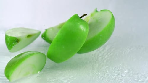 Slo-motion green apple falling into wedges