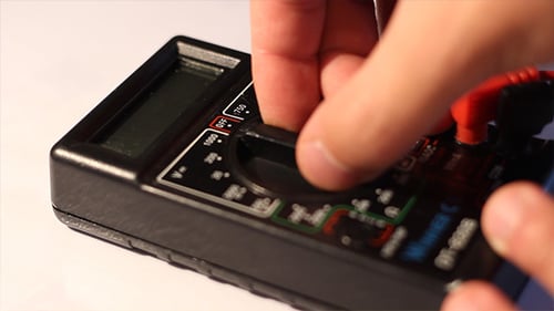 Hand Turning a Multimeter Dial Close Up