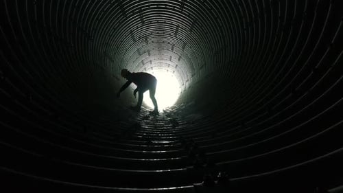 Figure Working Inside a Large Metal Drainage Tunnel