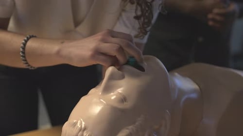 A Close Shot Of A Female Placing An Oral Airway Device On A Mannequin's Mouth