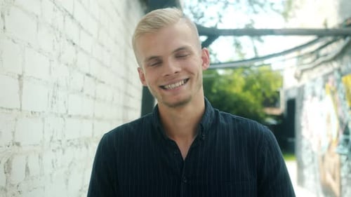 Young Man Smiling in an Urban Alleyway