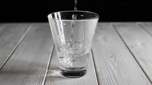 Water Filling Glass on White Wooden Table