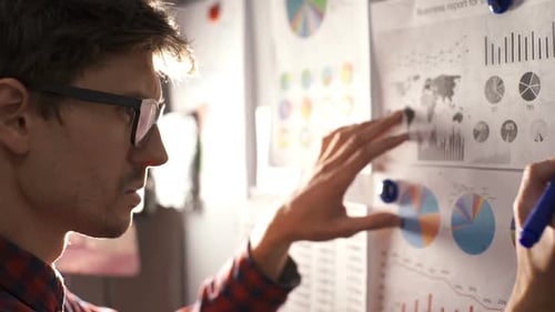 Man Analyzing Business Charts with Marker in Office