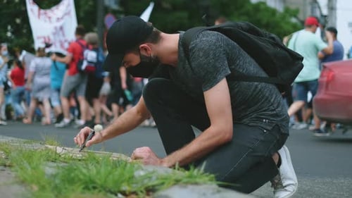 Man Drawing Sign at an Urban Protest