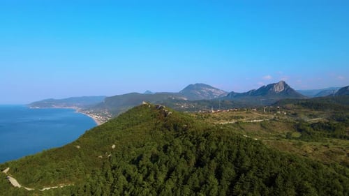 steile grüne Berge, tiefe Wald- und Bergstraße, schönes Tal und blaues Meer