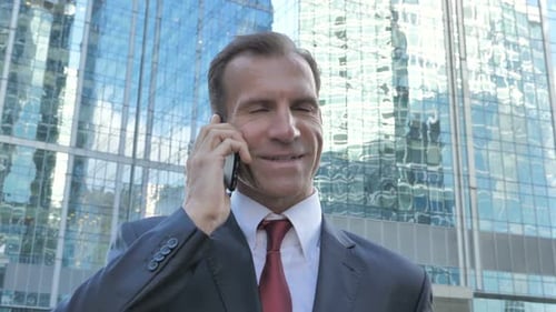 Business Man Talking on Smartphone Near Modern Building
