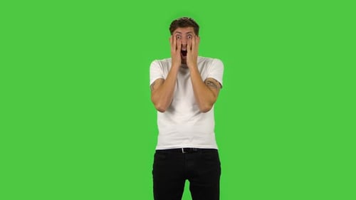 Selbstbewusster Kerl Horror schaut und bedeckt sein Gesicht mit seinen Händen. Greenscreen