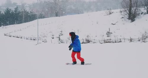 Männlicher Snowboarder fährt in Zeitlupe auf einem Brett im Schnee von der Skipiste