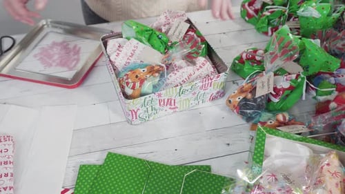 Hands Packing Christmas Cookies into a Festive Tin