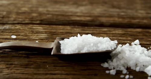 Salt in spoon on wooden table 4k