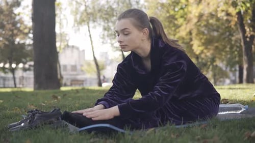 Woman Stretching in Park on Yoga Mat