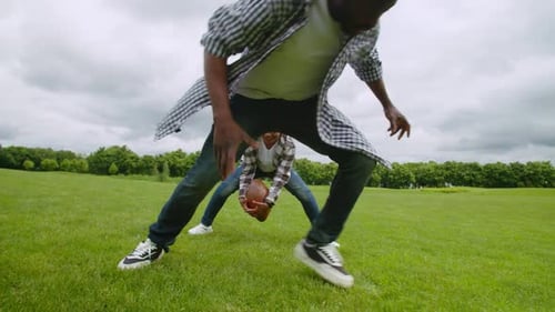 Father and Child Playing Football on Grassy Field