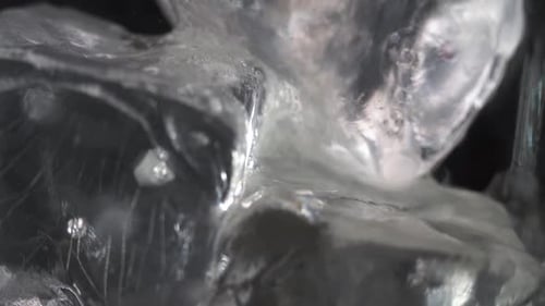 Extreme Close Up Ice Macro Footage Slow Motion. White Ice on Black Background. Pouring Light Yellow