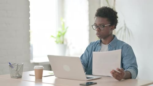 Young African Man Working on Documents in Office