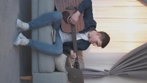 Young Adult Playing Guitar at Home
