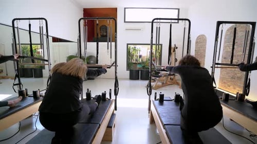 Women Exercising Pilates Reformer Machines in Studio