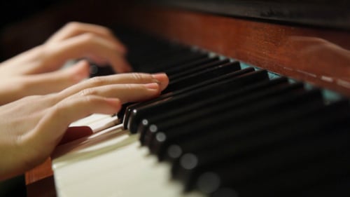 Hands Play Piano Keys in Close Up View