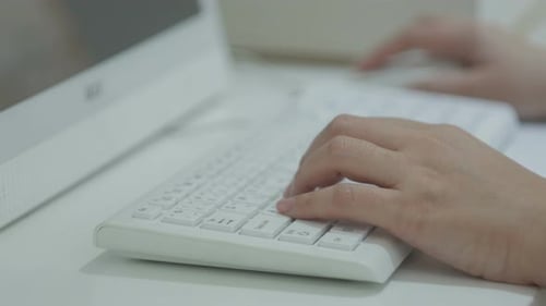 Hands Typing on a Modern White Keyboard