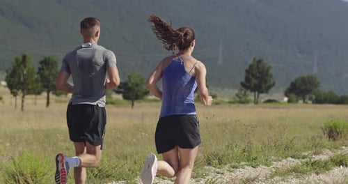 Tracking Slow Motion Shot of Sportive Couple Jogging Outdoors in the Morning Trail Running