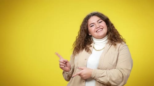 Smiling Woman Pointing to the Left on Yellow Background